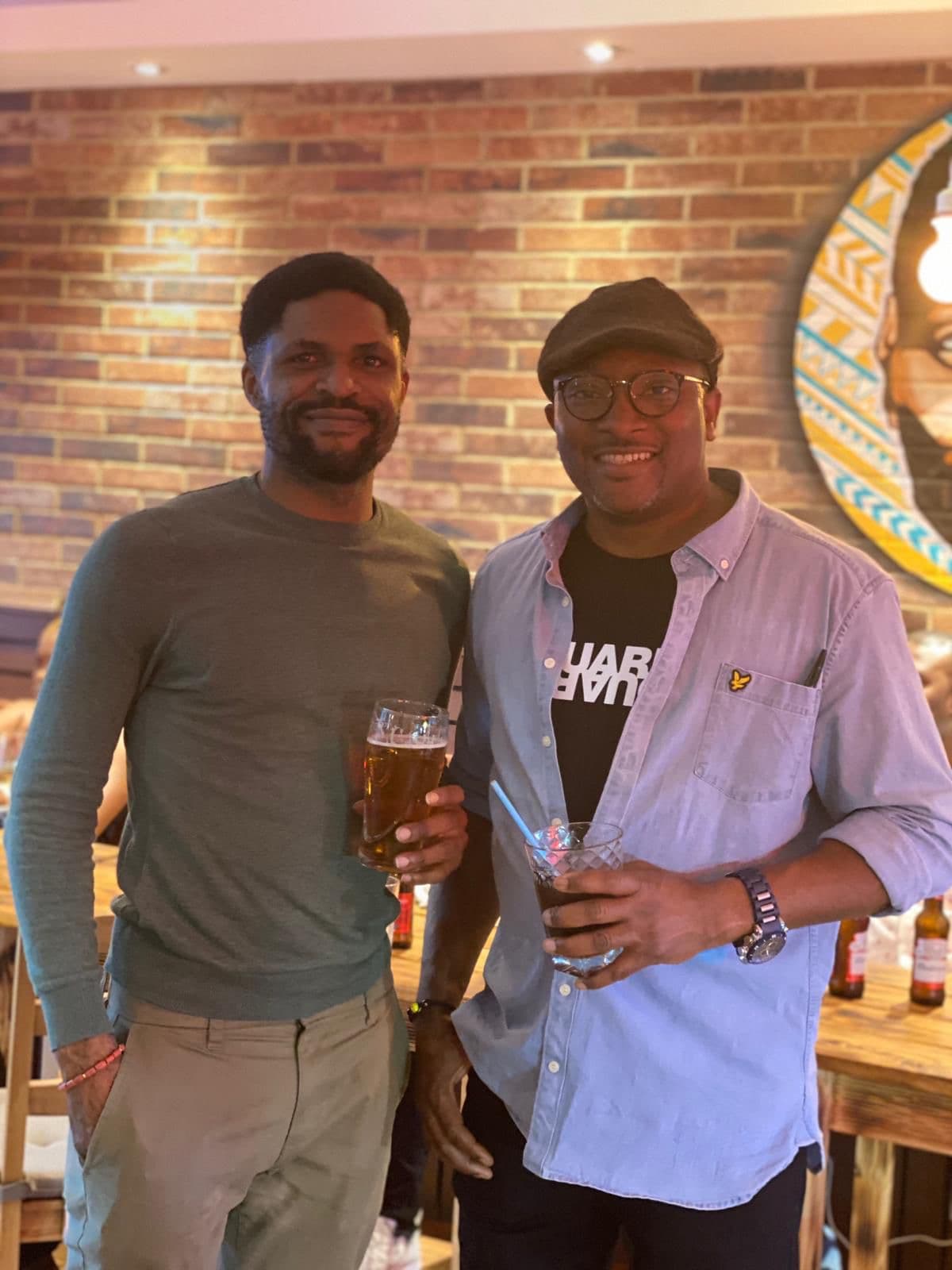 Two friends chatting over drinks at a community evening.
