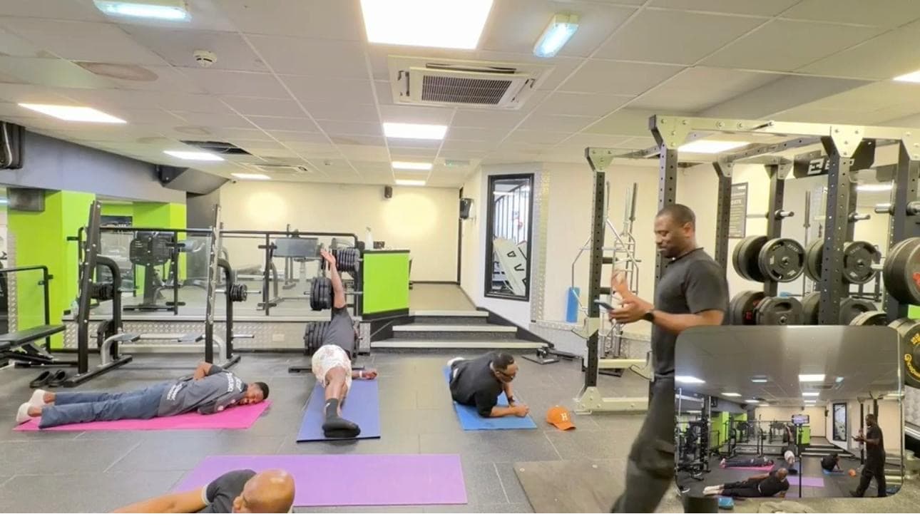 Men It's OK members in a guided gym session, working through mat exercises together.